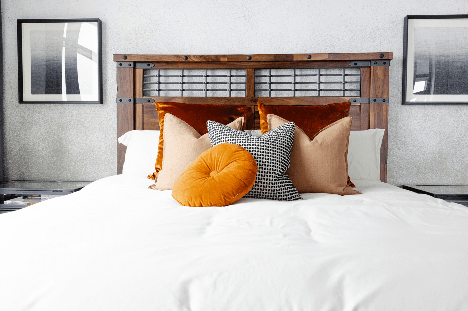 Cabecero de madera con ropa de cama blanca y cojines de tonos cálidos
