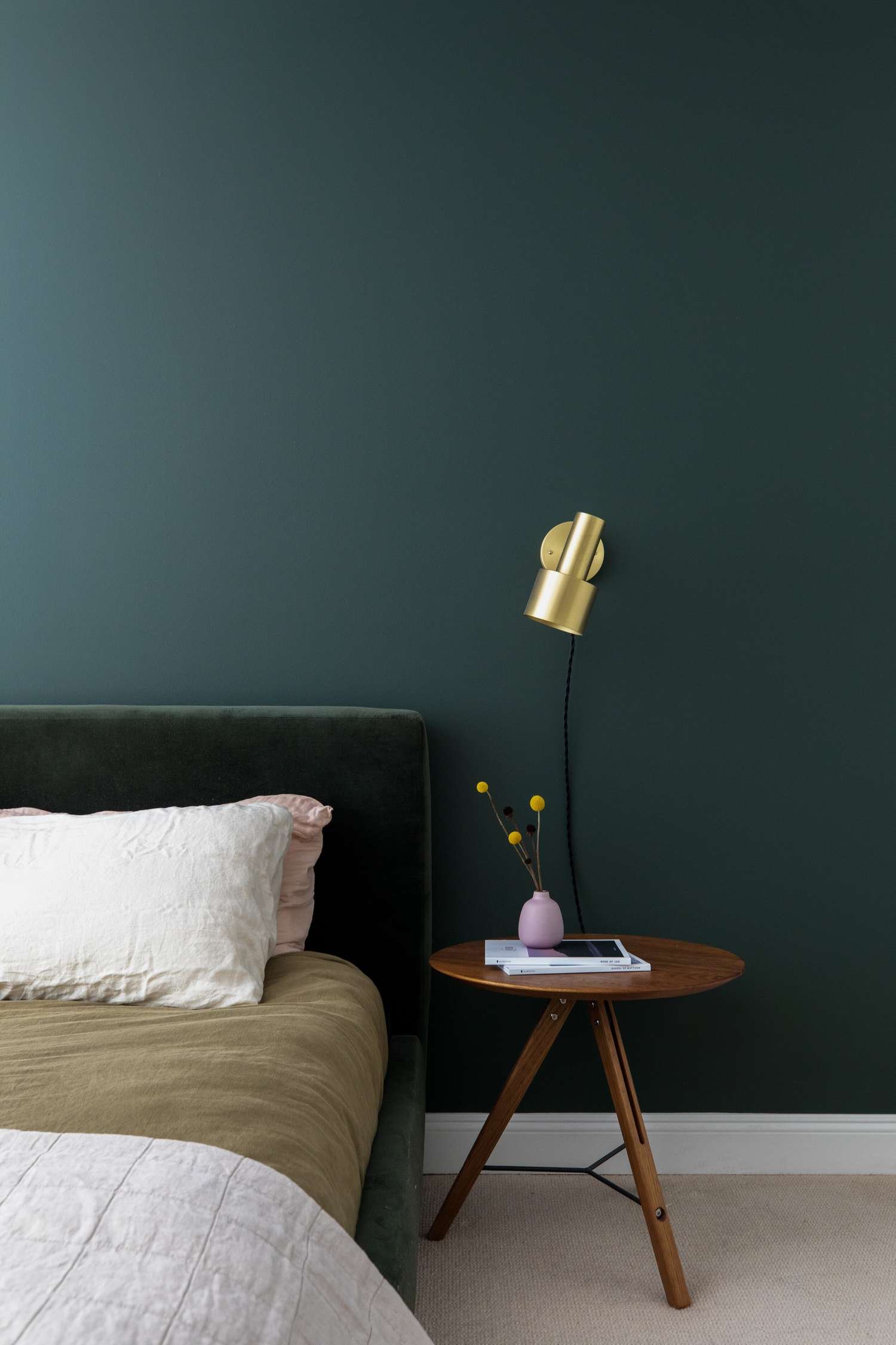 dormitorio verde oscuro con aplique de latón