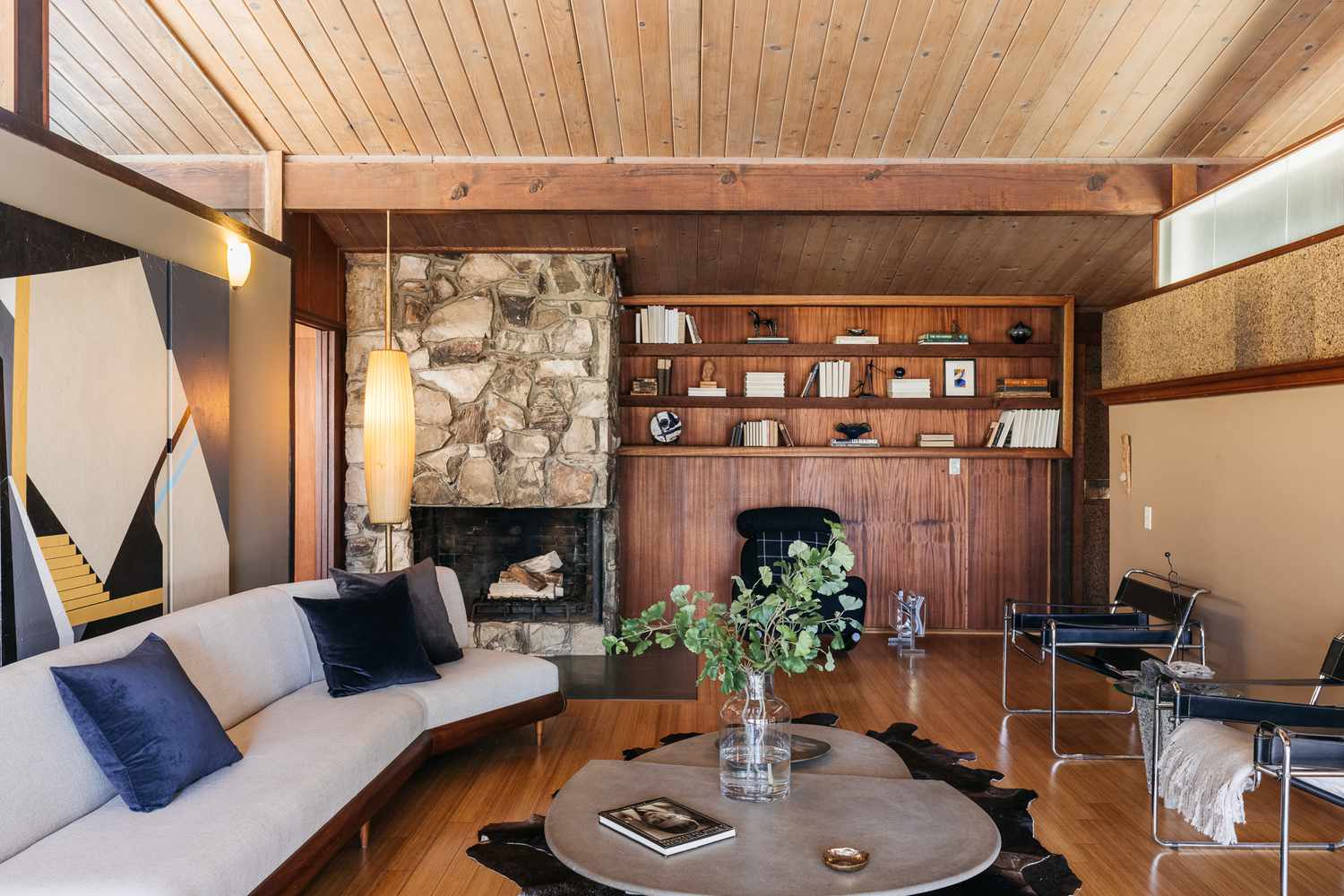 Salón moderno de mediados de siglo con estanterías de madera y asientos modernos