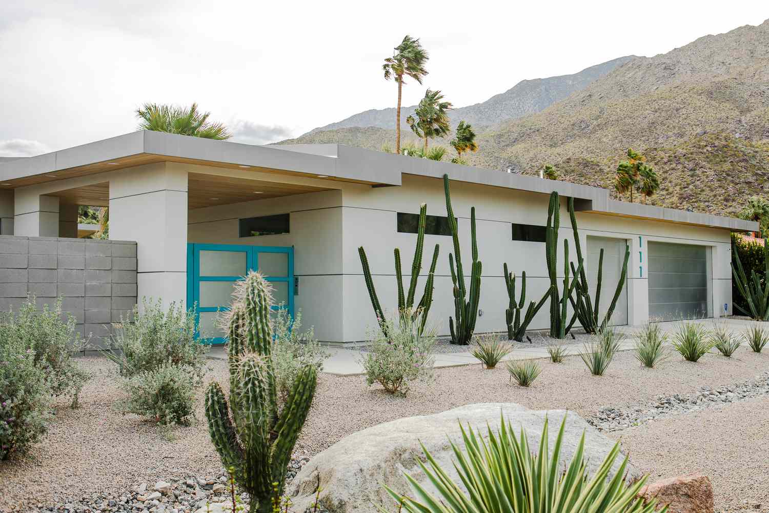 Casa moderna blanca situada en un paisaje desértico con puerta de garaje azul brillante