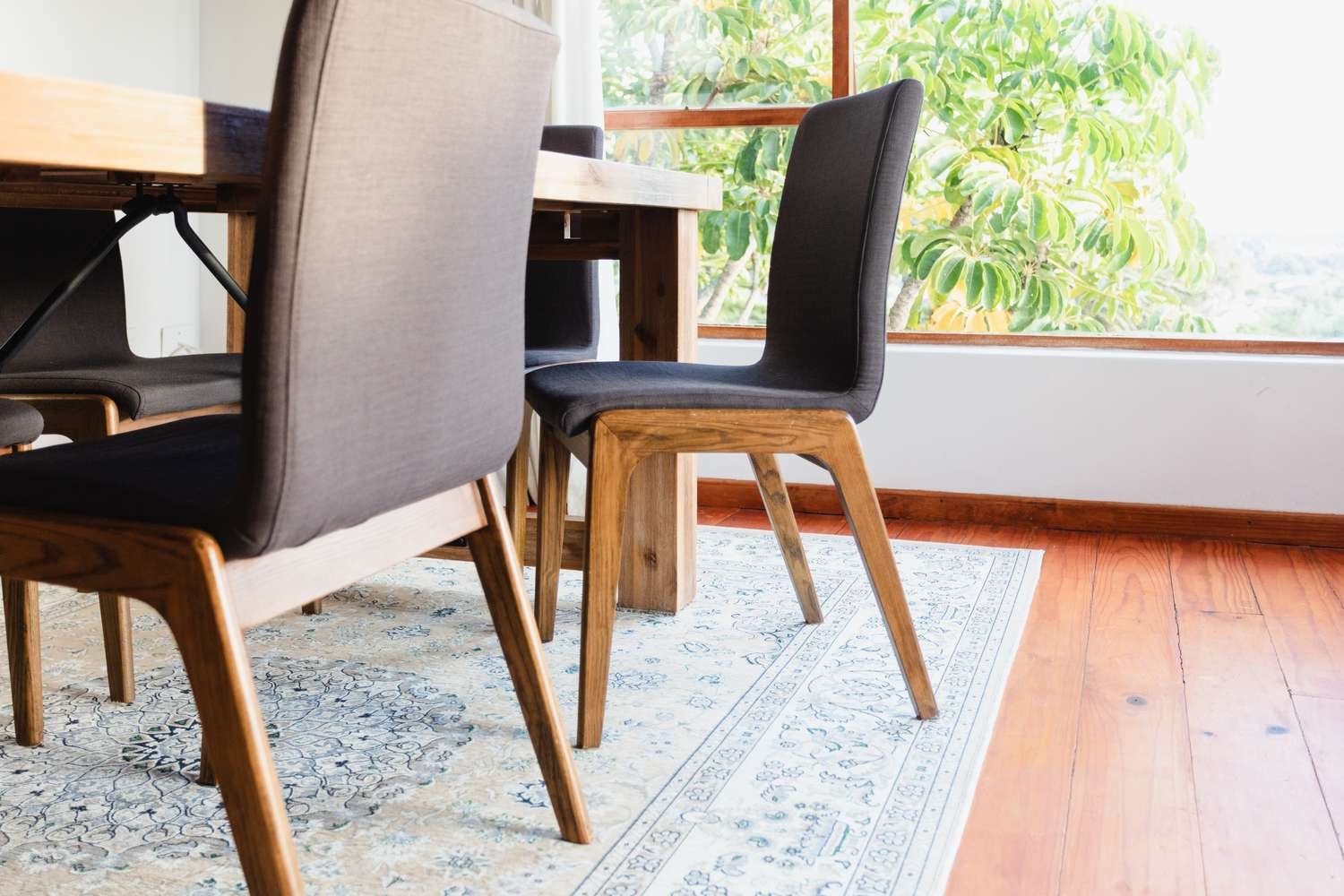 Alfombra de color claro bajo la mesa del comedor con las sillas de comedor retiradas