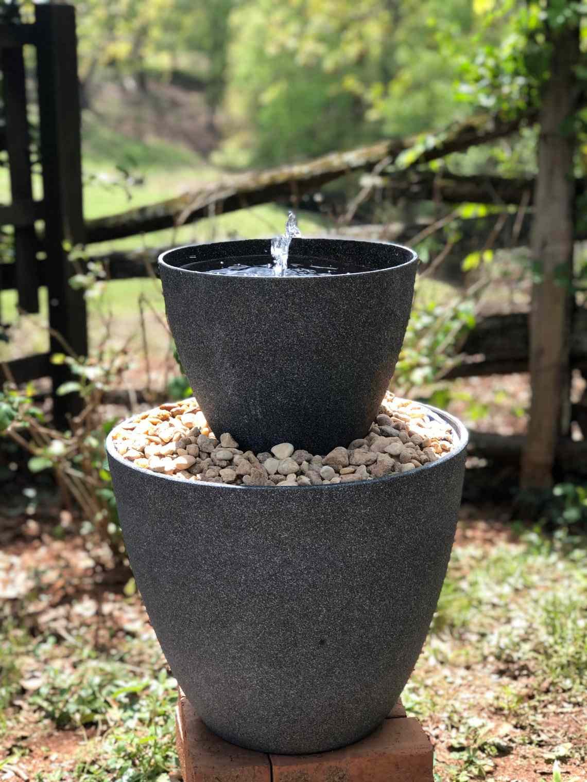 Agua burbujeando en una fuente negra de dos niveles para exteriores.