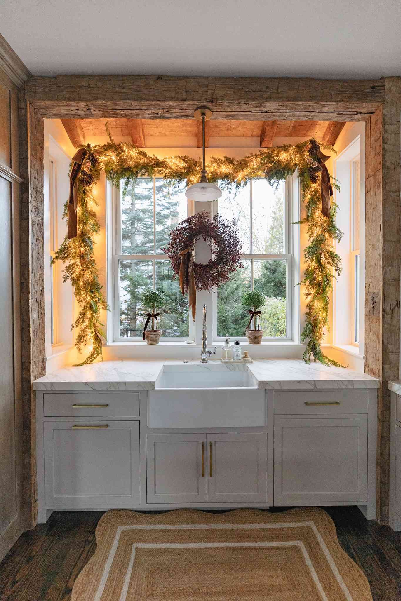 Guirnalda de vegetación con cintas y luces centelleantes colgada alrededor de una ventana de cocina