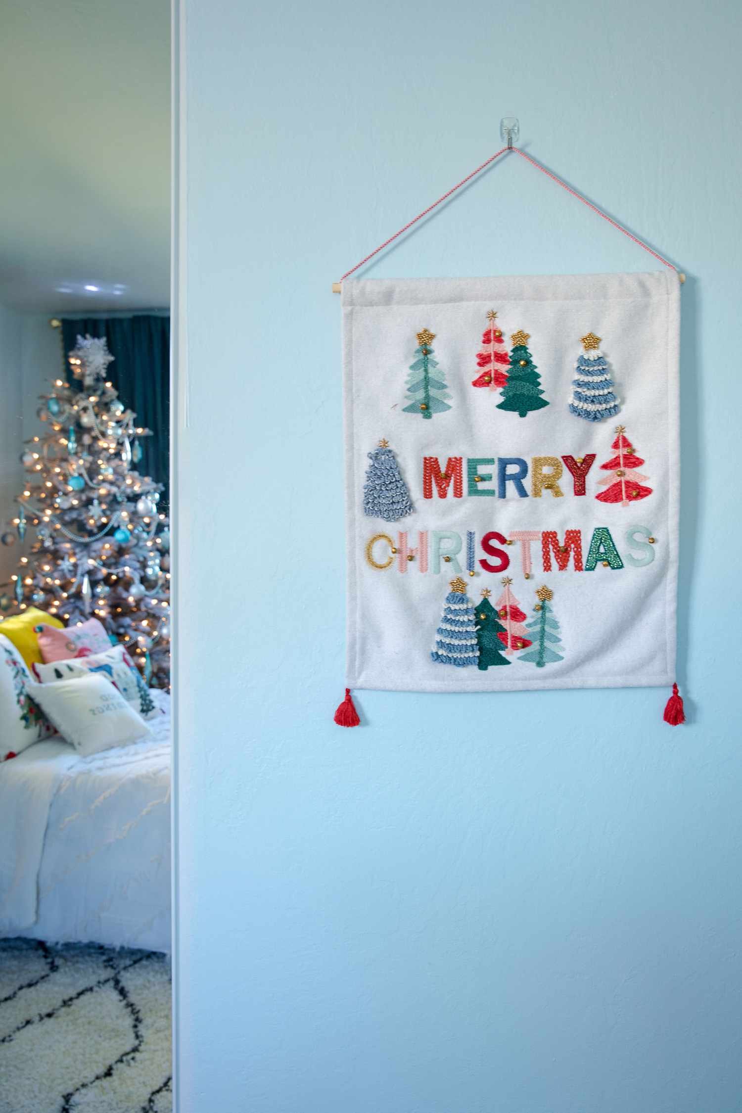 Bordado navideño colgado en una pared azul claro