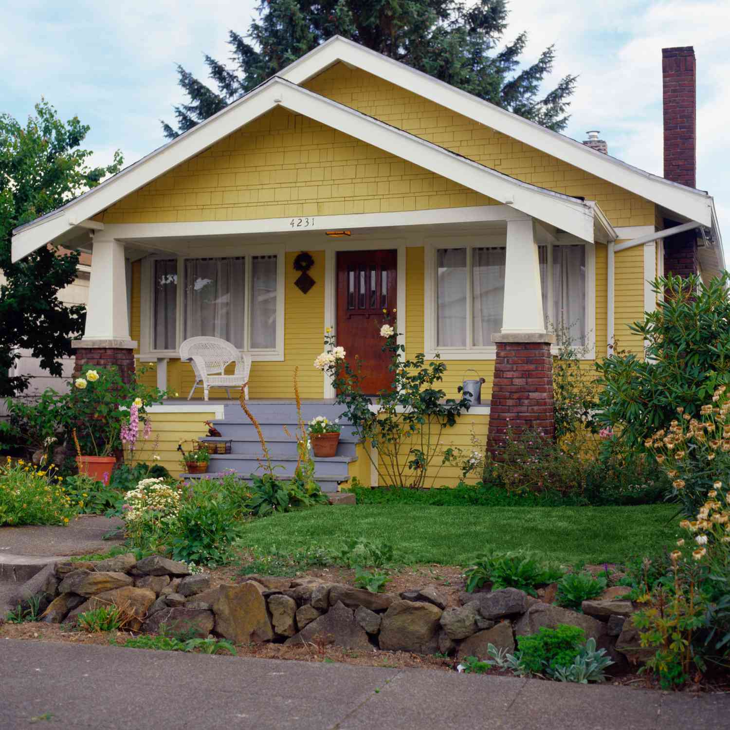 Casa amarilla estilo bungalow con jardín, vista exterior