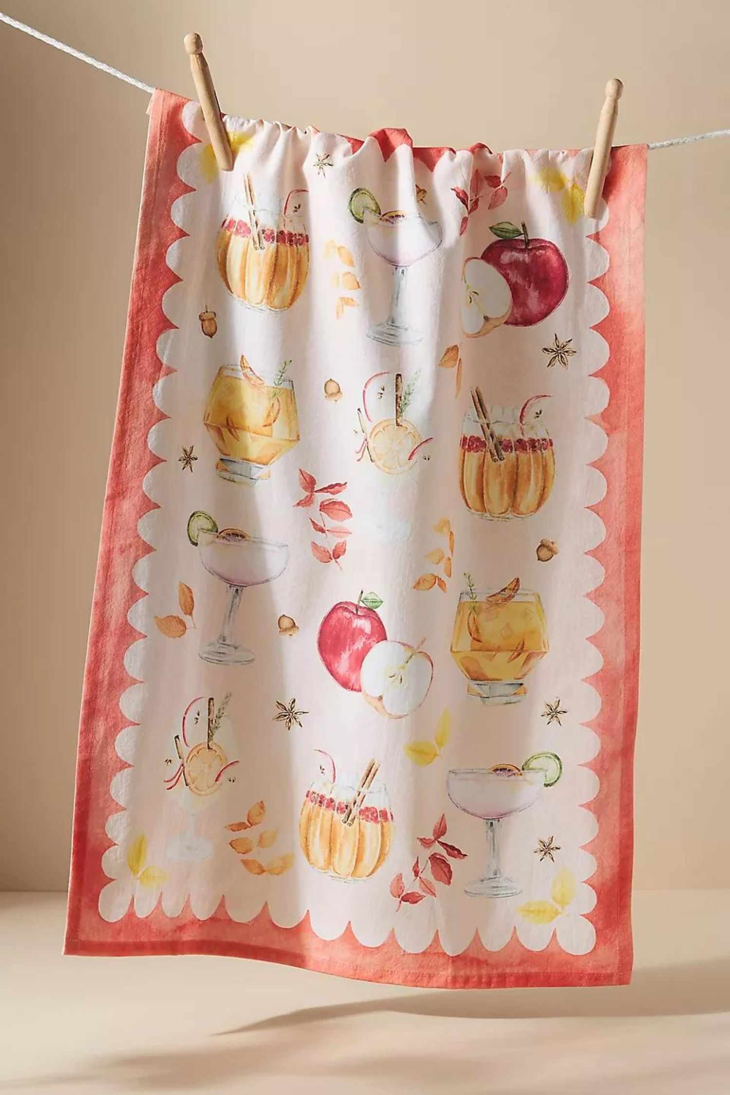 Un paño de cocina festoneado con estampado de acuarela y dibujos de cócteles de otoño, especias y manzanas