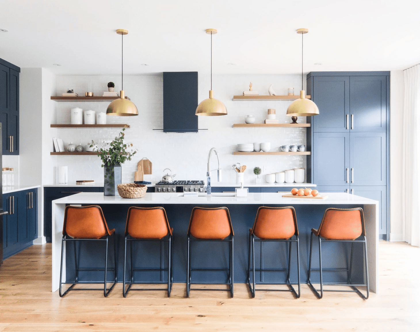 Una cocina con armarios azules y taburetes naranjas