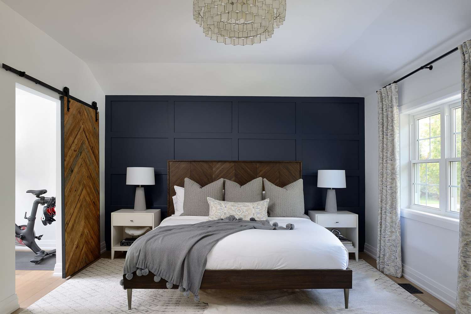 Un dormitorio elegante con una cama de madera chevron y una puerta de granero de madera chevron a juego