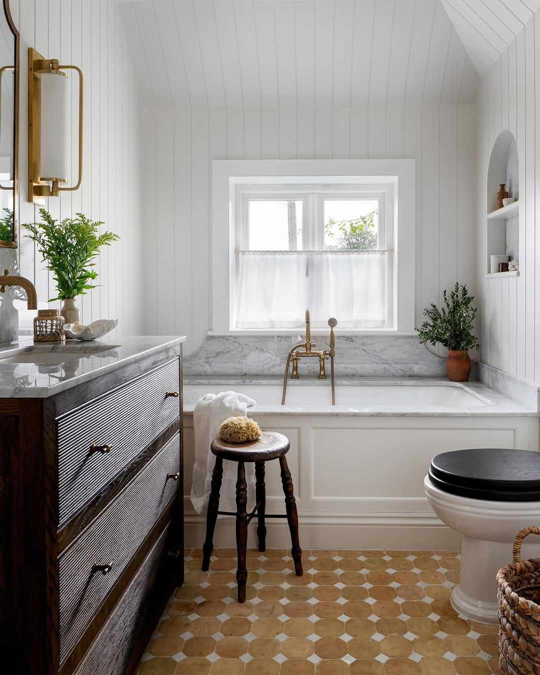 Baño blanco clásico con toques de madera rústica, salpicadero de mármol y suelo de baldosas blancas y tostadas 