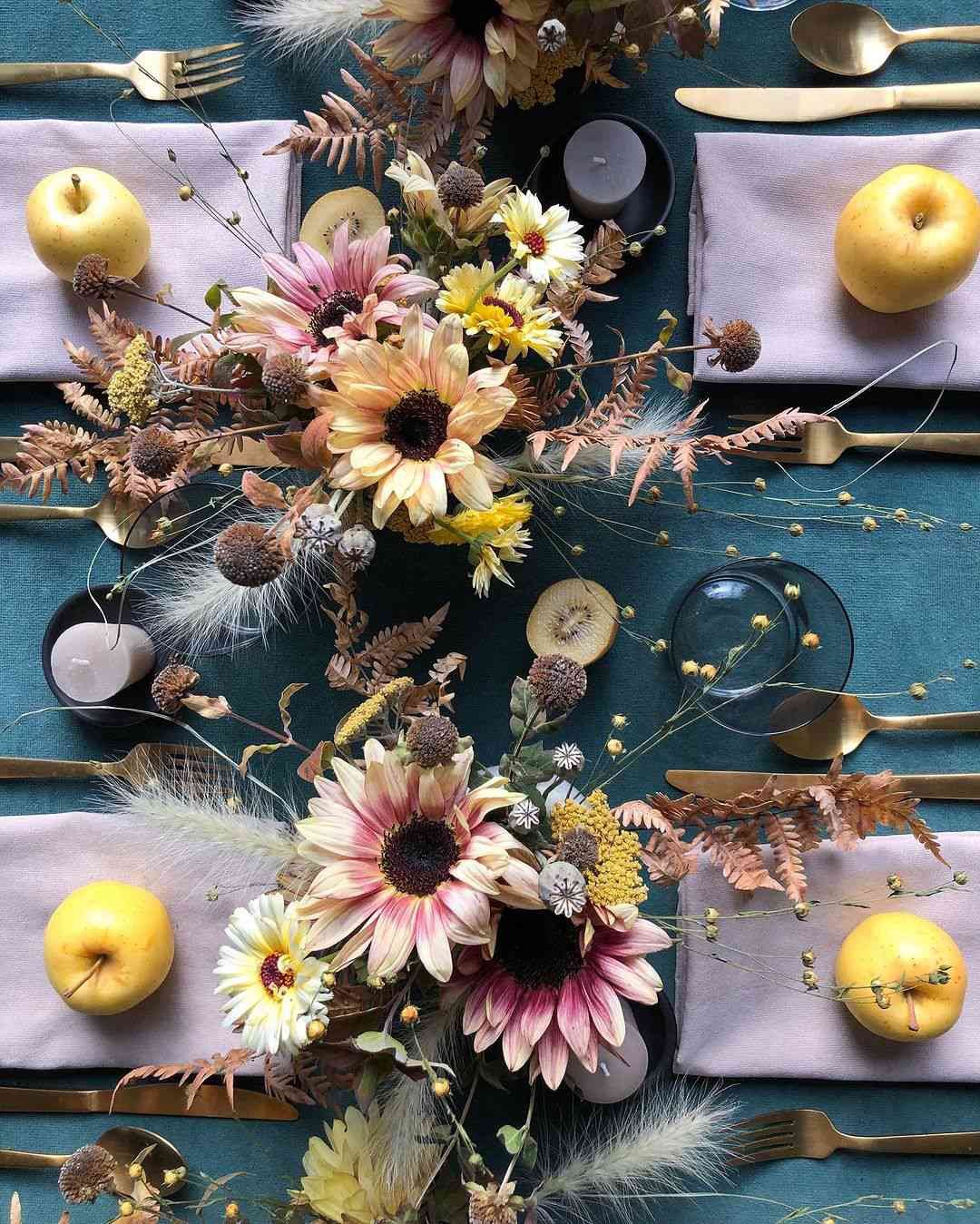 Mesa con cubertería dorada, manzanas y flores